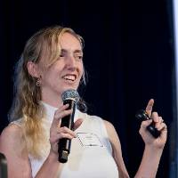 Scholar presenting with microphone in hand.